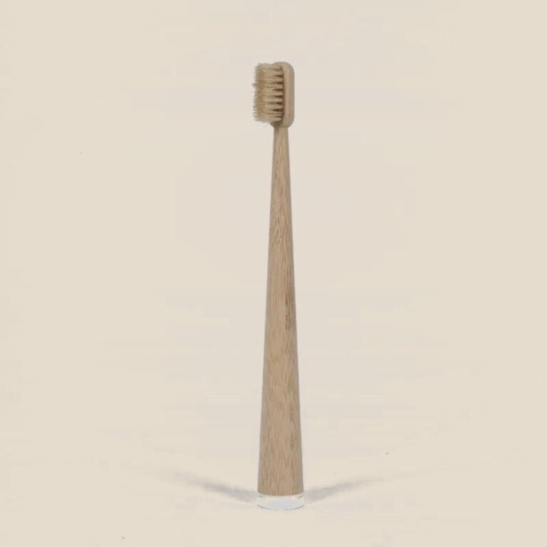Escova de bambu com cerdas naturais, em pé sobre fundo areia